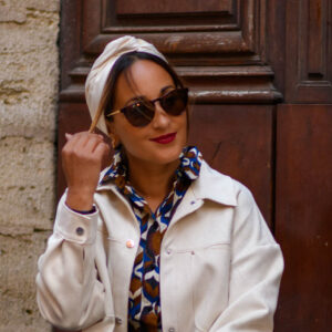 Modèle femme NDJ Occitanie portant le bandeau cheveux Eve crème en satin, noué façon turban, fabrication artisanal.
