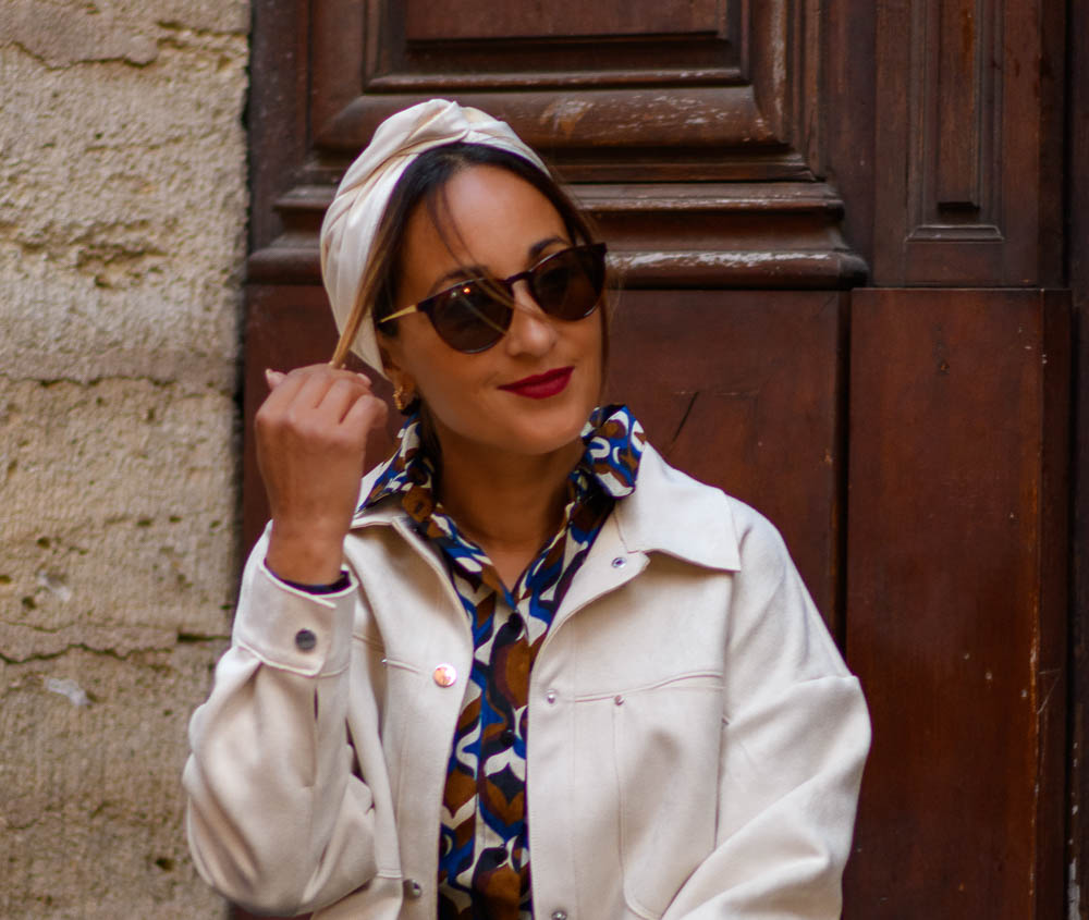 Modèle femme NDJ Occitanie portant le bandeau cheveux Eve crème en satin, noué façon turban, fabrication artisanal.