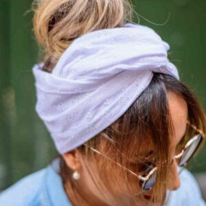Modèle femme NDJ Occitanie portant le bandeau cheveux Isa en broderie anglaise blanche, noué façon turban, fabrication artisanal.