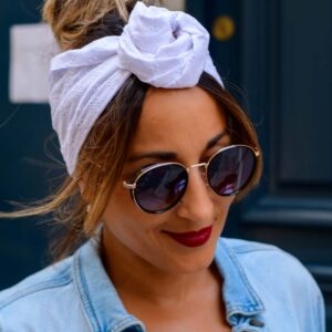 Modèle femme NDJ Occitanie portant le bandeau cheveux Isa en broderie anglaise blanche, noué façon rose africaine, fabrication artisanal.