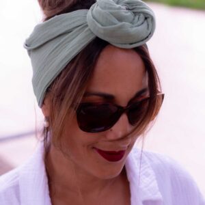 Modèle femme NDJ Occitanie portant le bandeau cheveux femme noué façon rose africaine Jade fabriqué à la main en gaze de coton Kaki.
