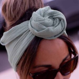 Modèle femme NDJ Occitanie portant le bandeau cheveux femme Jade noué façon rose africaine fabriqué à la main en gaze de coton Kaki.
