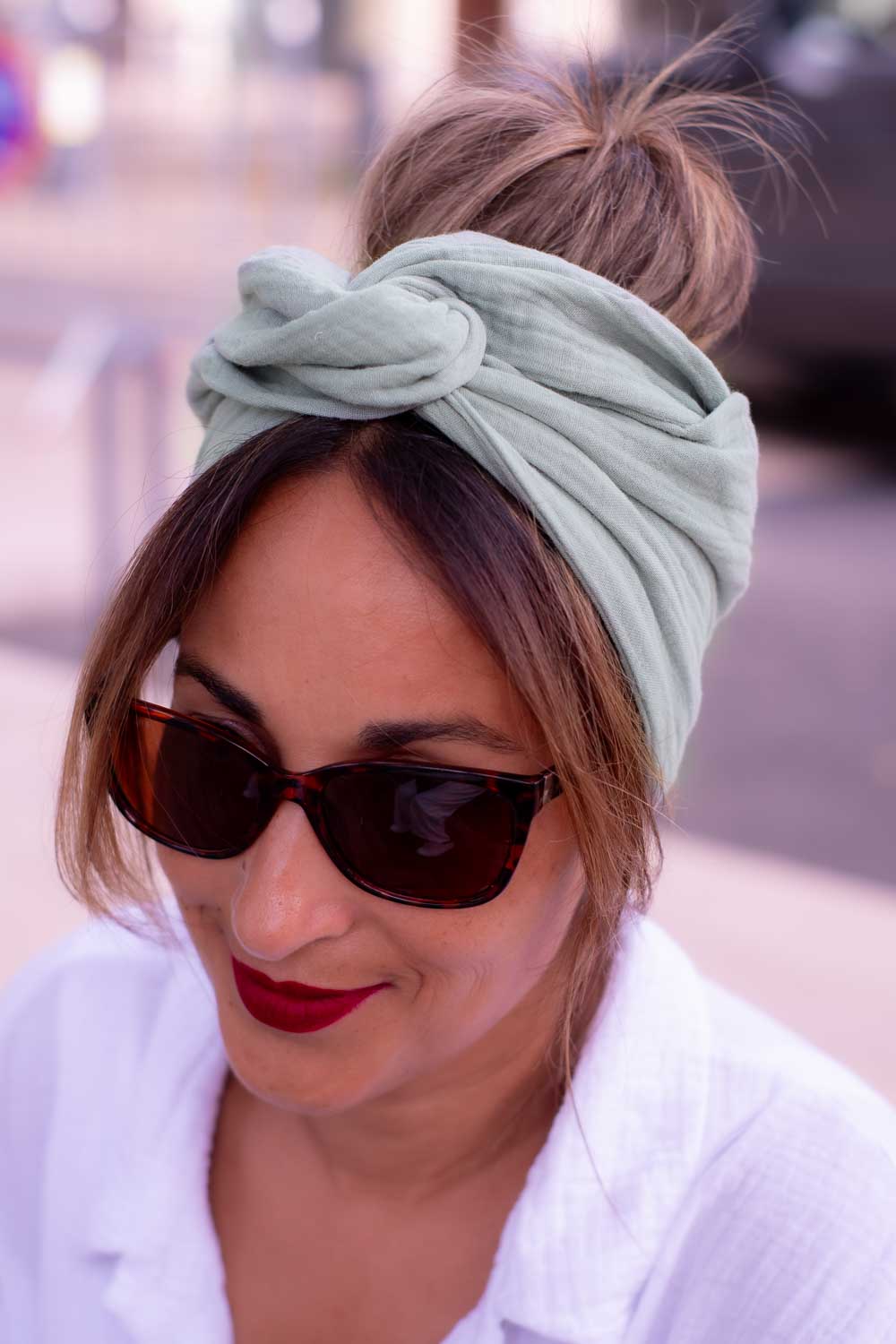 Modèle femme NDJ Occitanie portant le bandeau cheveux femme Jade noué façon turban fabriqué à la main en gaze de coton Kaki.