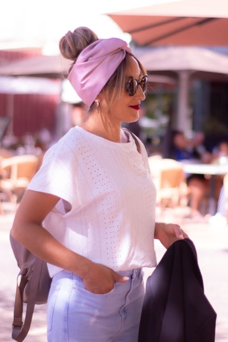 Modèle femme NDJ Occitanie portant le bandeau turban rose Livia en satin, noué façon turban, fabrication artisanal.