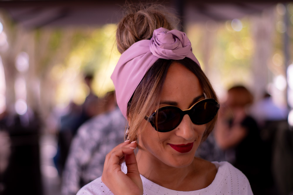Modèle femme NDJ Occitanie portant le bandeau turban rose Livia en satin, noué façon rose africaine, fabrication artisanal.