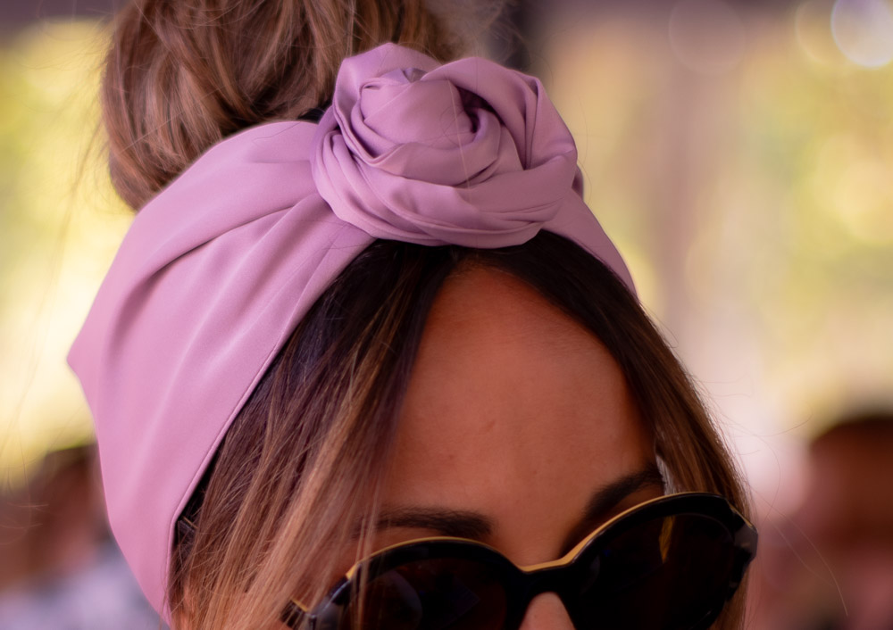 Modèle femme NDJ Occitanie portant le bandeau turban rose Livia en satin, noué façon rose africaine, fabrication artisanal.